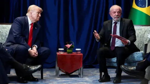 Lula e Trump em reunião bilateral em Washington, sentados em poltronas com a bandeira do Brasil ao fundo