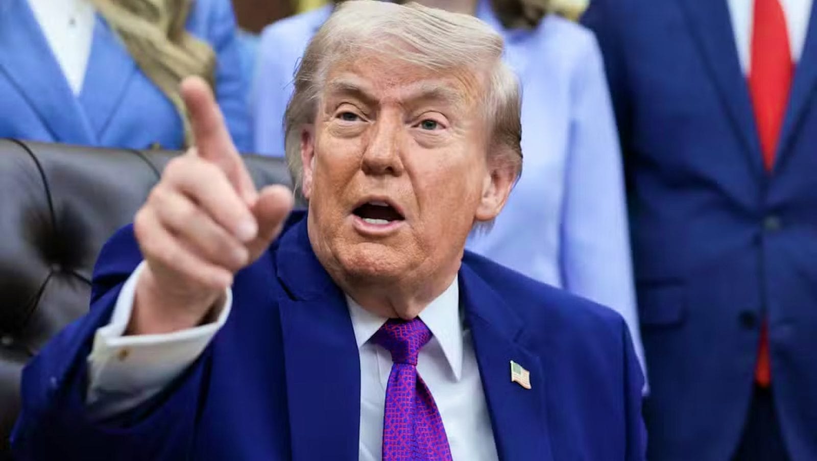 Donald Trump aponta o dedo durante coletiva, vestido com terno azul