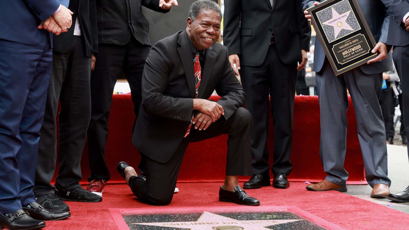 Paulinho da Costa ajoelhado ao lado de sua estrela na Calçada da Fama de Hollywood