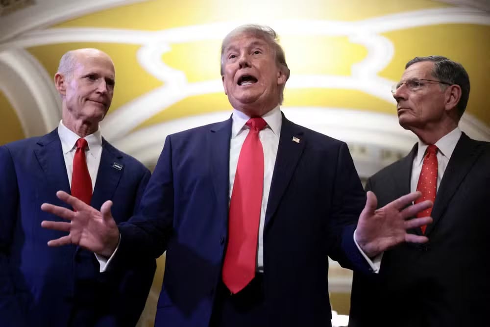 Donald Trump gesticula ao falar com jornalistas no Capitólio, ladeado pelos senadores Rick Scott e John Barrasso