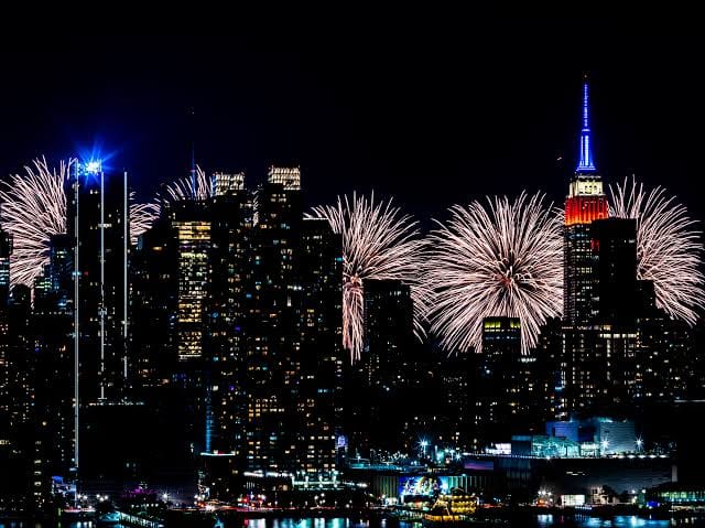 Fogos de artifício iluminam o céu de Nova York ao redor do Empire State Building aceso em vermelho, branco e azul