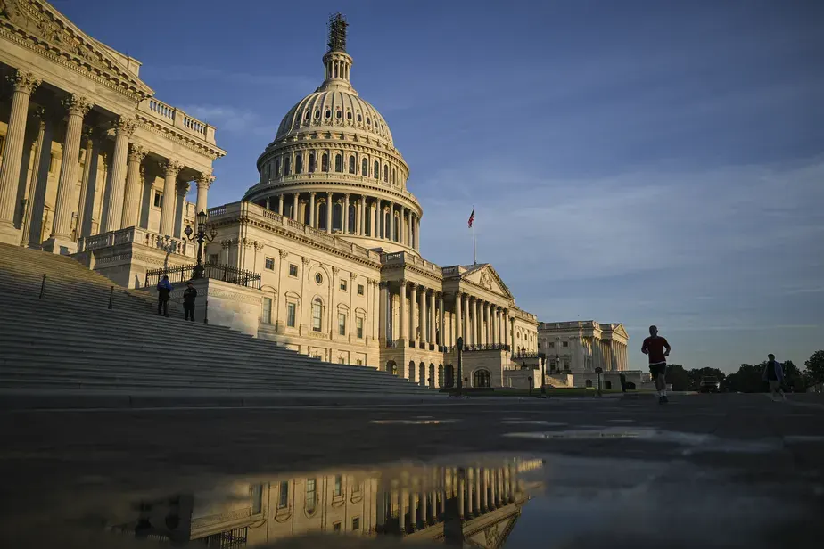 Cúpula do Capitólio dos EUA, em Washington, ao amanhecer, refletida em uma poça d'água