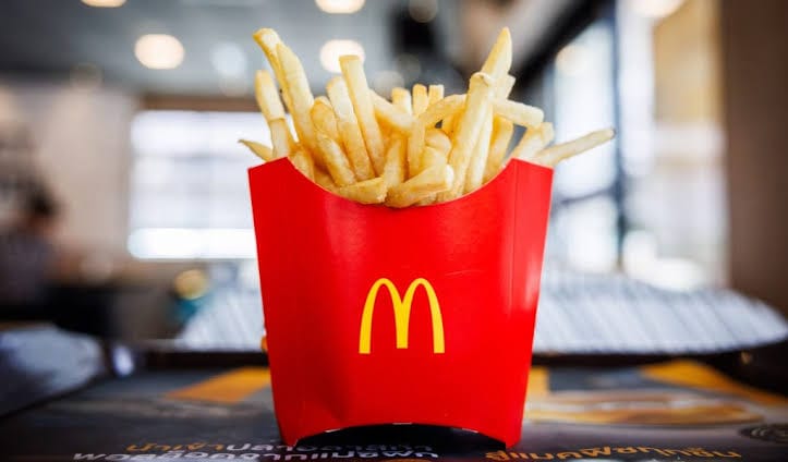 Embalagem vermelha de batata frita média do McDonald's sobre mesa, com o logo dourado em destaque