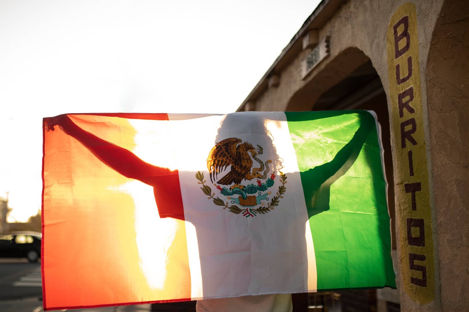Bandeira mexicana ao entardecer, em frente a uma loja de burritos