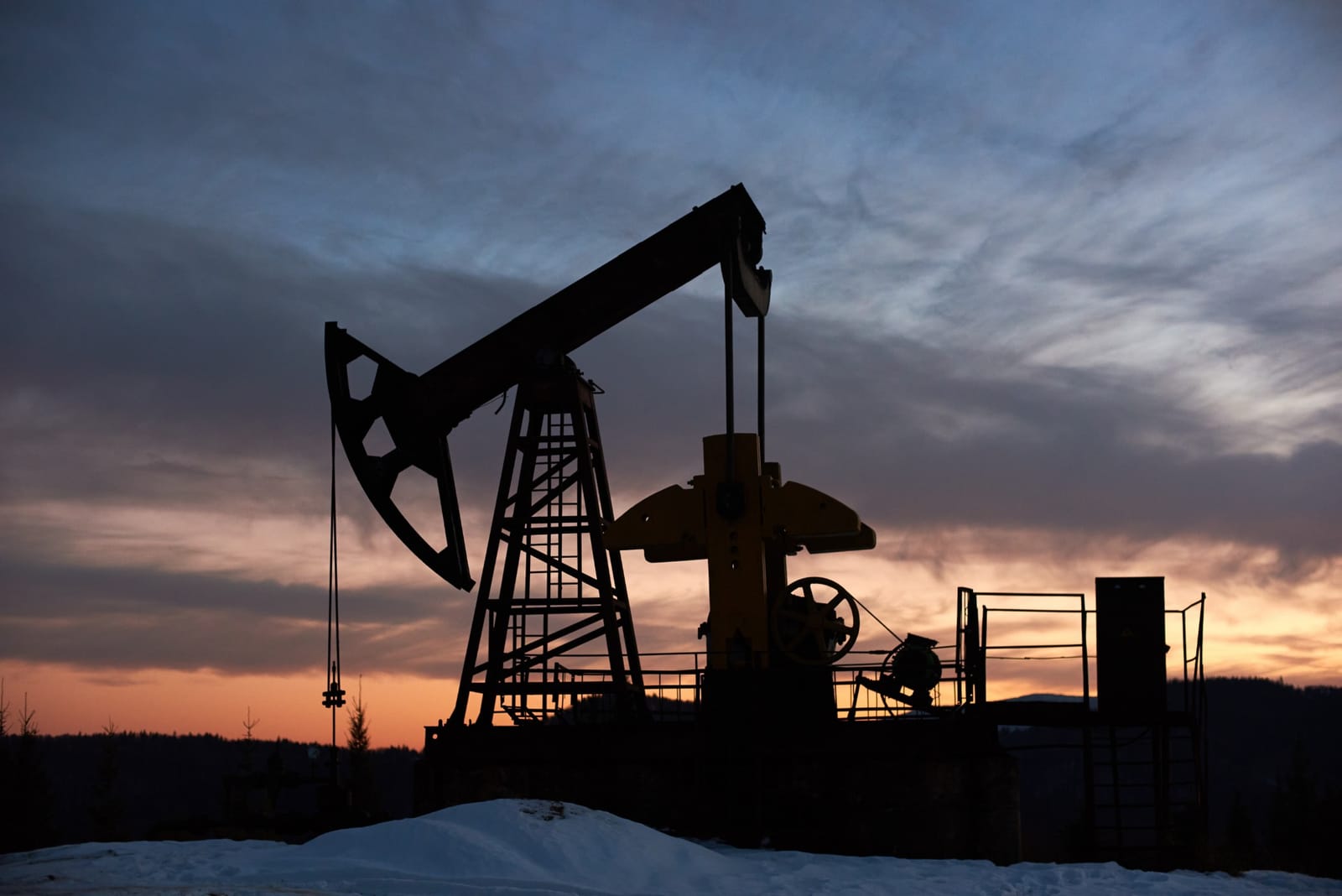 Silhueta de bomba de extração de petróleo contra o céu ao entardecer