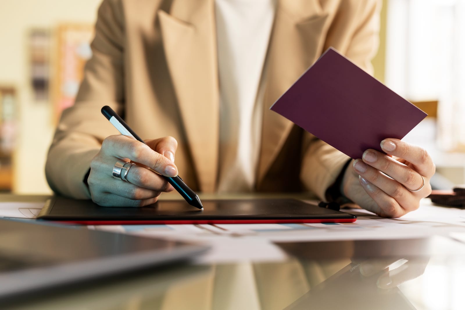 Pessoa segurando um passaporte e assinando em uma tela digital com caneta stylus