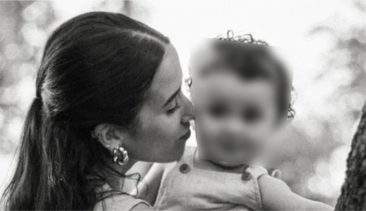Mulher de cabelos longos beija o rosto de um bebê de colo em foto em preto e branco; o rosto da criança aparece desfocado para preservar a privacidade