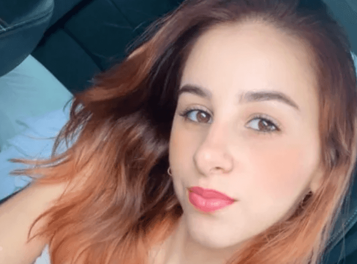 Selfie de Camila Bravin, jovem de cabelos ruivos ondulados, olhando para a câmera