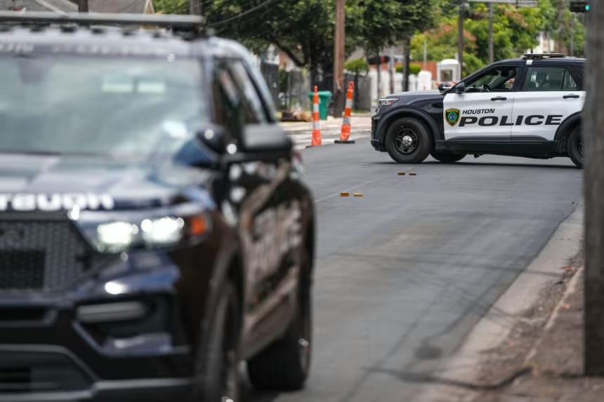 Duas viaturas da polícia de Houston isolam uma rua residencial, com marcadores de evidência no asfalto entre os carros