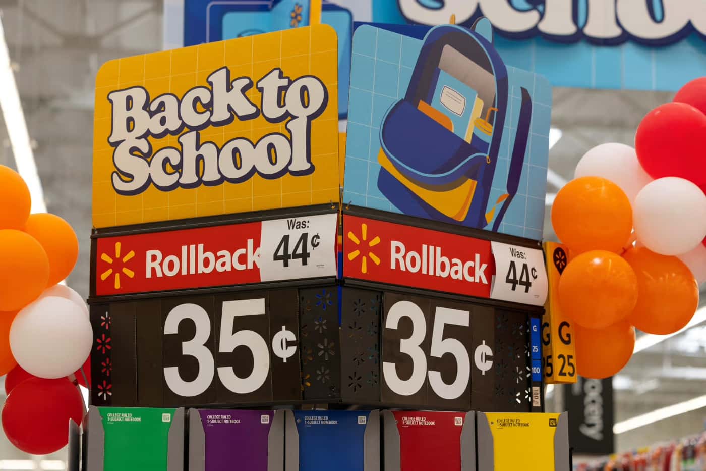 Expositor de volta às aulas em loja do Walmart com placas Rollback anunciando cadernos a 35 centavos, valor anterior de 44 centavos, cercado de balões