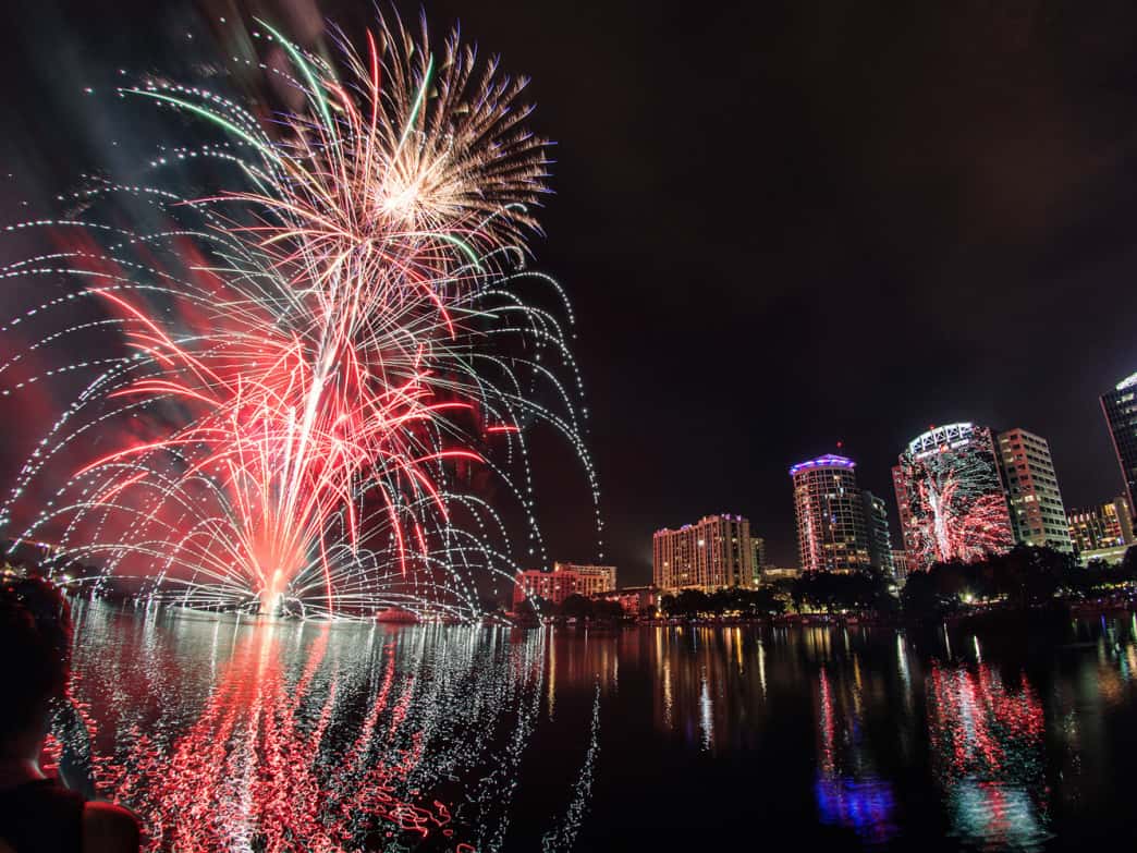 Show de fogos de artifício refletido na água durante celebração noturna em Orlando
